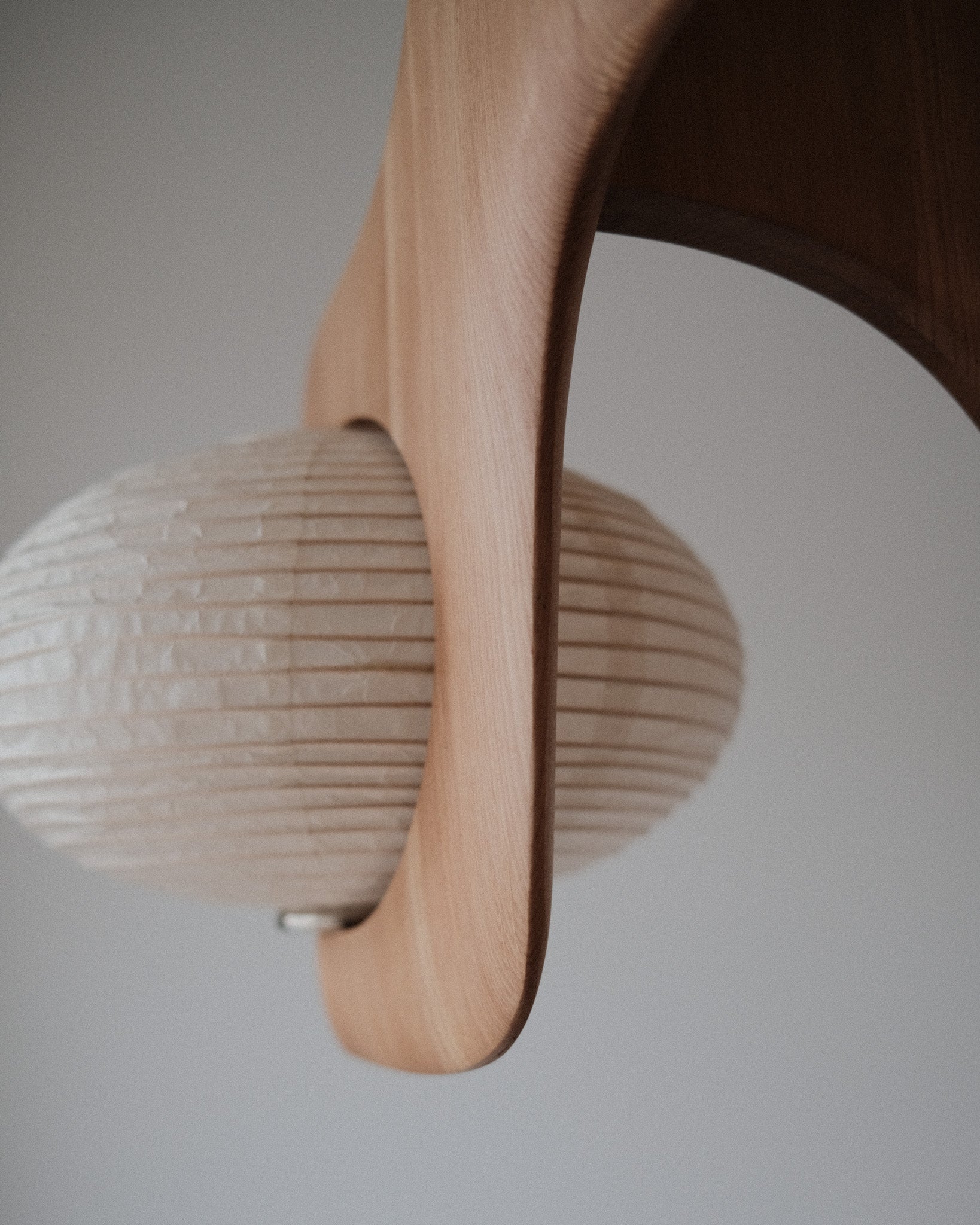 A detail shot of Kawabi's Cascade Pendant made of White Oak and kozo paper, focusing on the handcarved wood.