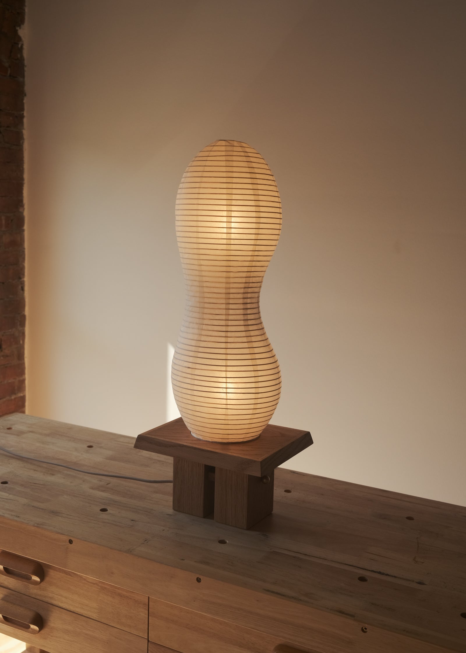 An isometric view of Kawabi's Legume Lamp made of Japanese washi and White Oak, gently glowing during sunset.