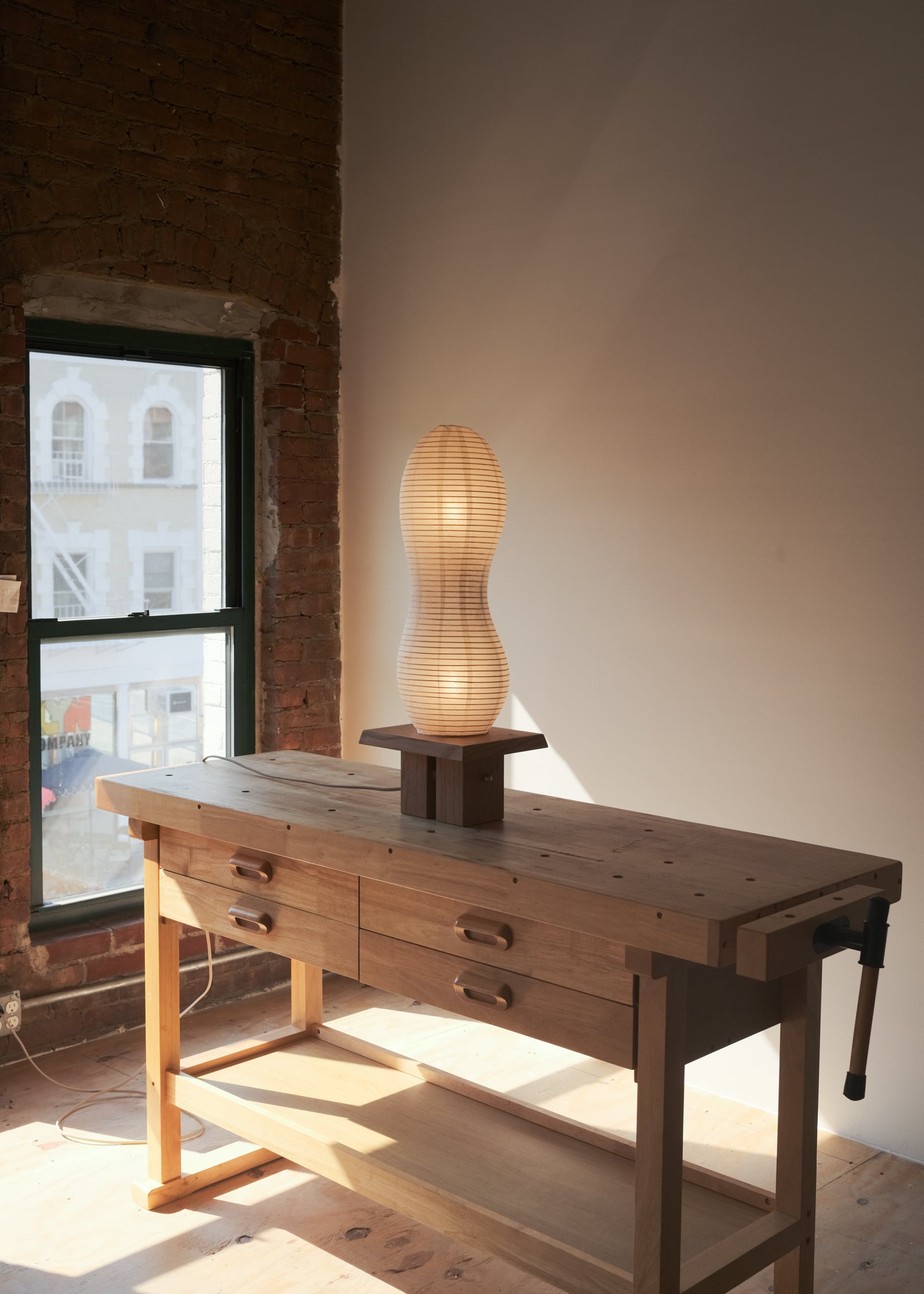 A view of Kawabi's Legume Lamp made of Japanese washi and White Oak in an airy, woodworking studio.