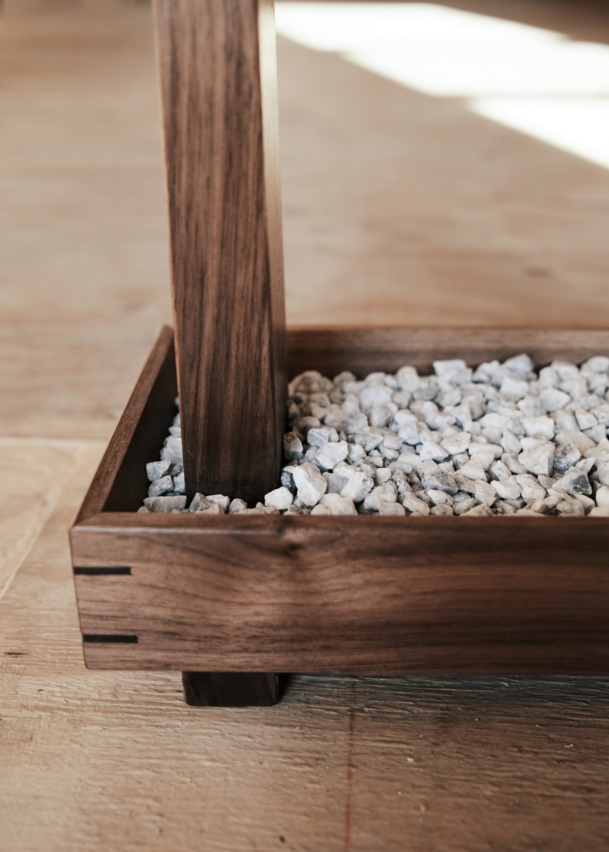 A close-up view of Kawabi's Souvenir Floor Lamp rock tray base, made with Walnut joinery and marble chips.