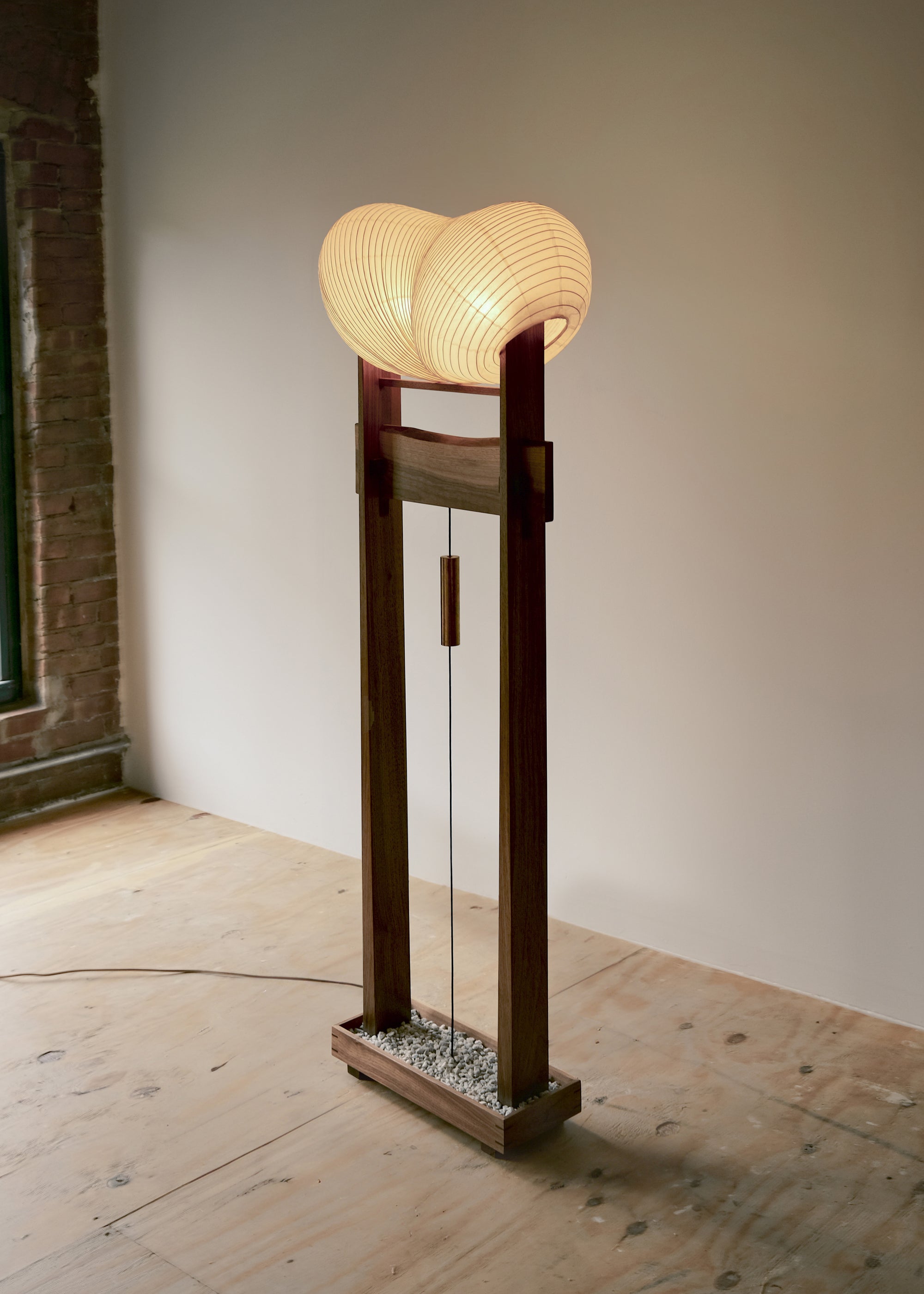 An isometric side view of Kawabi's Souvenir Floor Lamp lit up in their woodworking studio