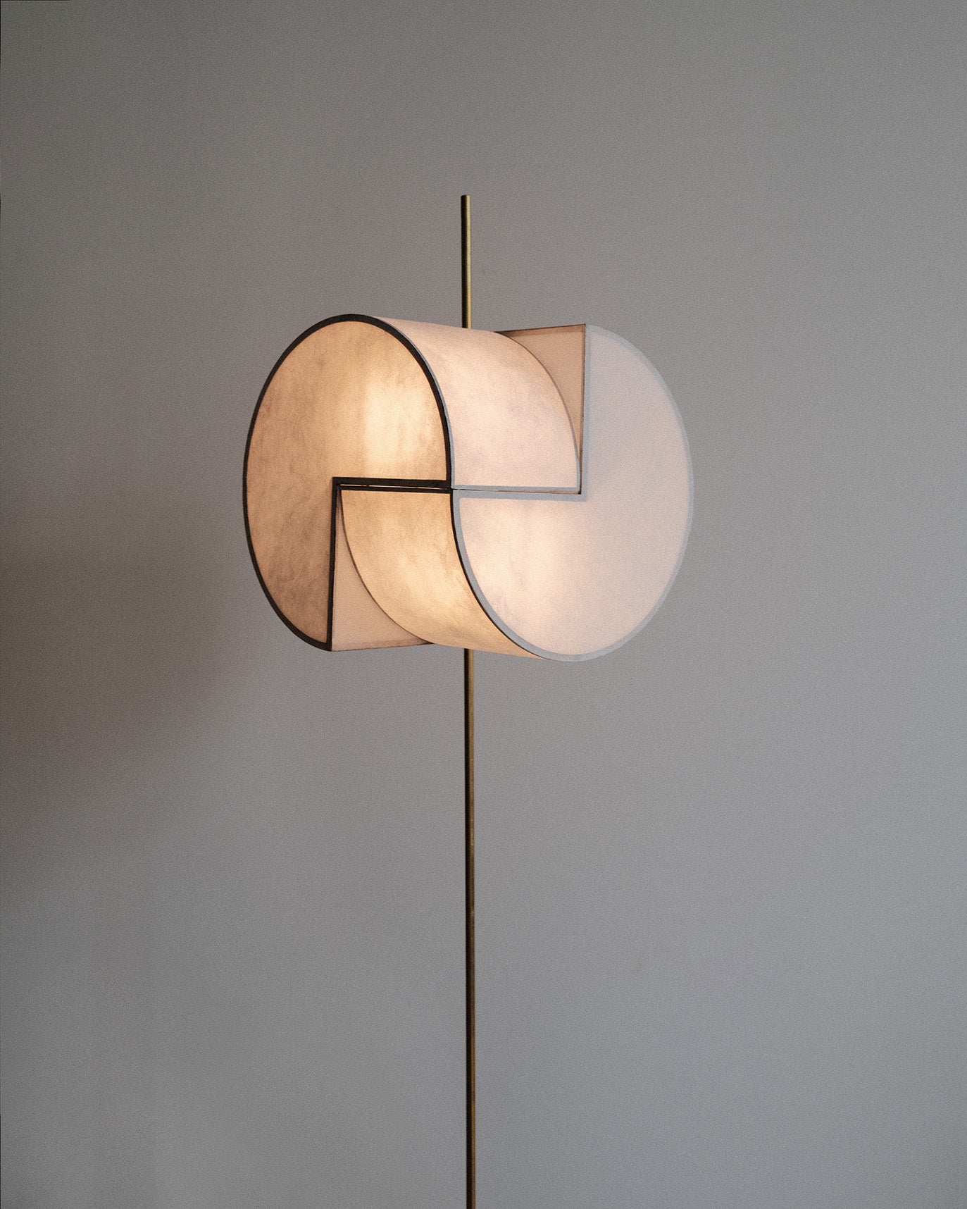 A geometric paper floor lamp made with Japanese washi and brass, resembling a three-dimensional pacman shape.